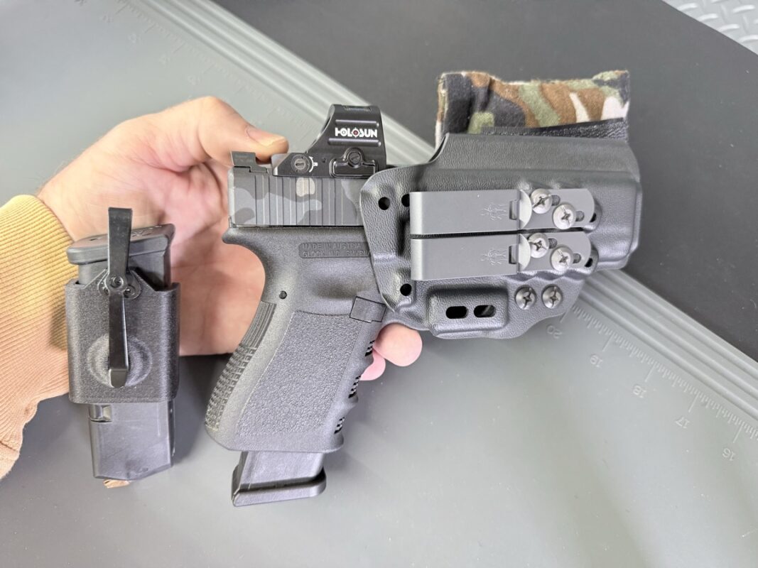 Everyday carry gear for the constitutional carry states 2026 list — a Glock with a Holosun red-dot in a Kydex AIWB holster fitted with a MultiCam Cloudster Pillow holster wedge, beside a Kydex magazine carrier